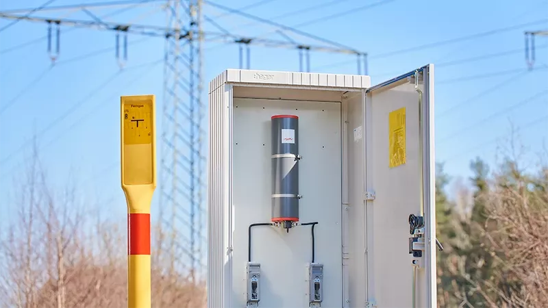 Abgrenzeinheit im Schutzgehäuse vor Hochspannungsleitung.